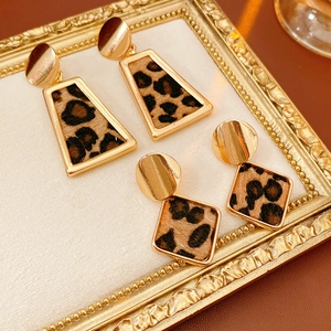 Détail de boucles d'oreilles léopard trapèze et carrées sur un cadre doré vintage