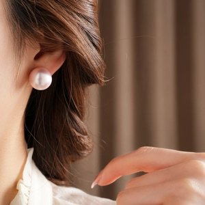 Detailed view of elegant pink pearl earrings with natural luster worn on a model's ear