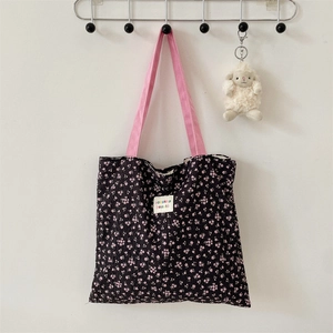 Detail of black pleated tote bag with pink floral print and canvas handle on wall hook