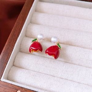 Detail of tulip earrings with red enamel petals and white pearls in a wooden box