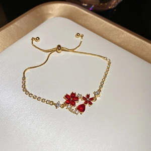 Detail of 18k gold plated bracelet featuring red flower charms and adjustable slide clasp