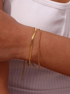 Detail of 18K gold-plated double-layer herringbone and snake chain on a model's wrist