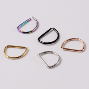 Detail of D-shaped nose rings in gold, silver, black, rose gold, and rainbow finishes