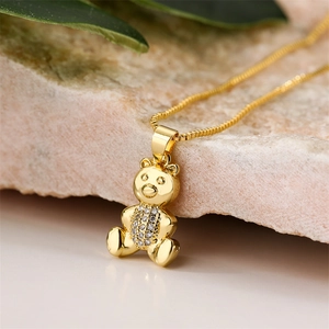 Macro shot of gold bear pendant necklace with pave zircons on a textured stone base