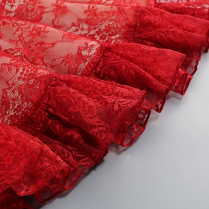 Detail of red floral lace hem with ruffled layers and delicate mesh textures
