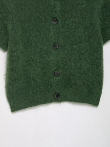 Dettaglio cardigan in maglia verde scuro con texture peluche e bottoni tondi