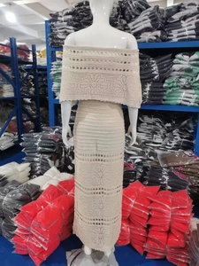 Dettaglio dell'abito in maglia traforata beige con scialle scoperto e taglio lungo