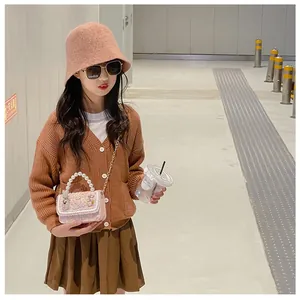 Girl's pink pearl handle crossbody bag styled with a brown knit cardigan outfit