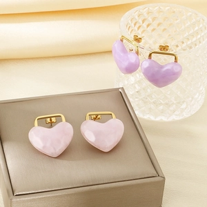 Detail view of pink and purple marble heart stud earrings on elegant silk fabric