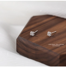 Close-up of S999 sterling silver rose stud earrings on a premium wooden display stand