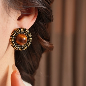 Close-up of vintage resin heart earrings with amber cat-eye stones on a model ear