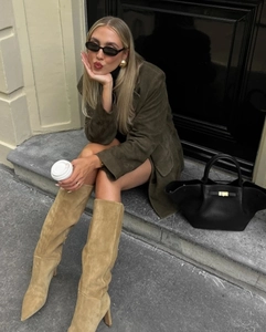 Chic women’s khaki suede high heel boots paired with olive jacket and black tote bag