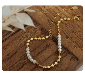 Macro view of gold-plated chain bracelet featuring glossy metal beads and freshwater pearls