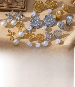 Close-up of vintage titanium steel earrings with heart, flower and pearl details