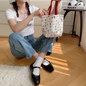 Borsa tote in tela floreale con manici rossi e stampe di orsi in un interno accogliente