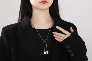 Detail of silver heart pendant and girl charm on adjustable snake chain necklace