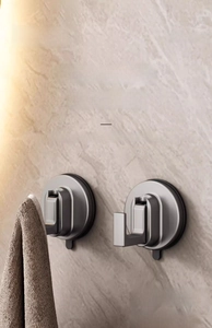Macro view of gray vacuum suction cup hooks with L-shaped design on marble bathroom wall