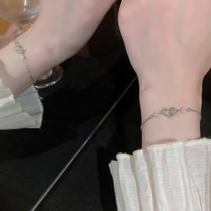 Macro shot of silver heart bracelet with cubic zirconia on a wrist with frilled cuffs