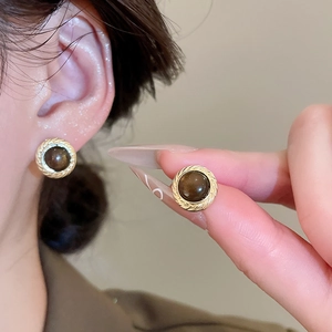 Close-up of vintage tiger eye stud earrings with golden spiral metal frame detail