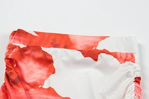 Close-up of red floral satin fabric with ruching details and smooth elastic waistband
