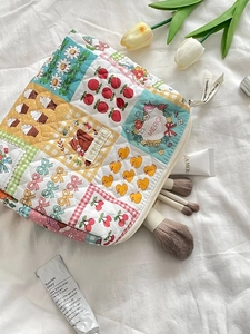 Detailed close-up of quilted floral makeup bag with cherry prints and zip puller