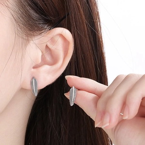 Detailed close-up of vintage silver feather stud earrings made of durable titanium steel