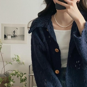 Detail of 925 silver pearl necklace styled with a dark blue knit cardigan on a model