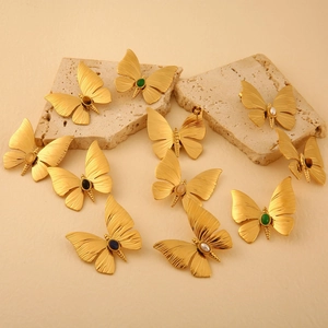 Golden dragonfly earrings with colorful natural stones arranged on a textured stone base