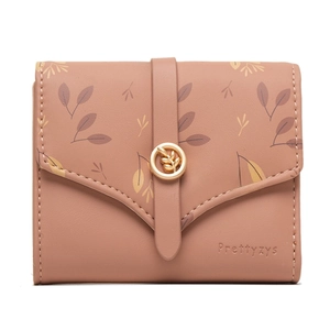 Close-up of dusty pink wallet featuring floral prints and gold leaf-shaped metal buckle