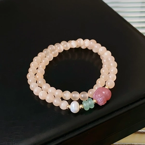 Detail of double-layer beaded bracelet with pink fluorite, pearls and carved pendant