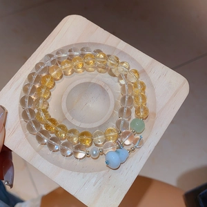 Detail of beaded bracelet set with yellow citrine, white chalcedony and a gourd pendant