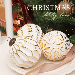 Detailed close-up of three 8cm white and gold Christmas balls with embossed patterns on a tray