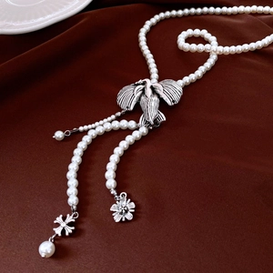 Detail of vintage bird pendant on pearl strand necklace with flower tassel accents