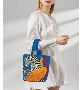 Artistic tote bag with zebra print and colorful wing patterns held by model in white dress