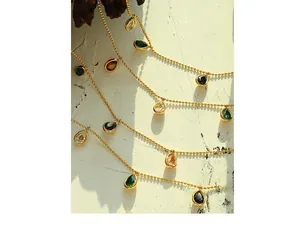 Detail of gold beaded chain necklace with multi-colored pear-cut gemstone pendants