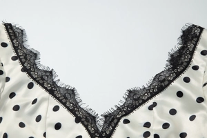 Dettaglio di un abito a pois stile francese con scollo a V in pizzo nero e raso