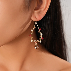 Gros plan sur des boucles d'oreilles bohèmes goutte avec perles rouges et champagne