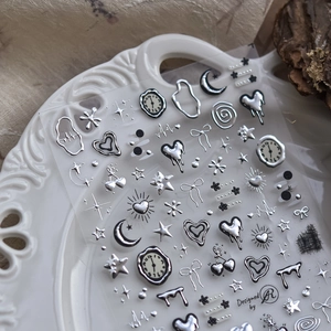 Silver metallic nail art stickers with fluid hearts, stars and moons on white plate