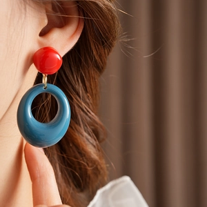 Close-up of retro resin geometric earrings with red studs and blue hollow pendants