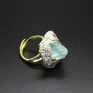 Macro shot of gold adjustable ring featuring a light blue raw stone and pave rhinestones