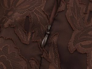 Détail de la texture jacquard marron foncé et de la fermeture éclair invisible de robe