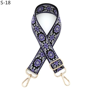 Detail view of ethnic embroidery purse strap with purple floral pattern and gold metal hooks
