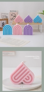 Close-up of heart and arch-shaped macaron scented candles on a wooden shelf and tray