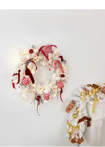 Close-up of white Christmas wreath with red ornaments, candy canes and warm LED lights