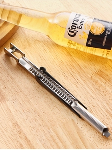 Close-up of a silver stainless steel bottle opener with black handle on wood surface