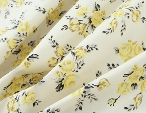 Detailed macro view of cream floral poplin fabric with yellow rose print and soft texture