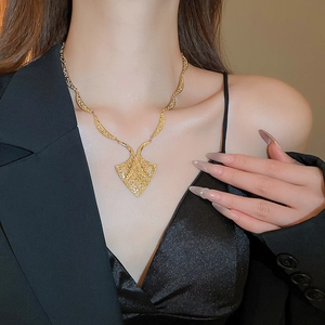 Detail of vintage gold geometric triangle pendant and textured chain on model