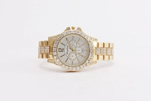Detailed macro view of gold-tone watch face featuring crystals and three sub-dials