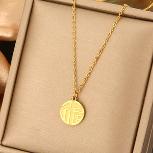 Close-up of golden pearl necklace with brushed finish Fu character pendant in a jewelry box