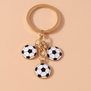 Detail of metal keychain featuring three black and white soccer charms on golden rings